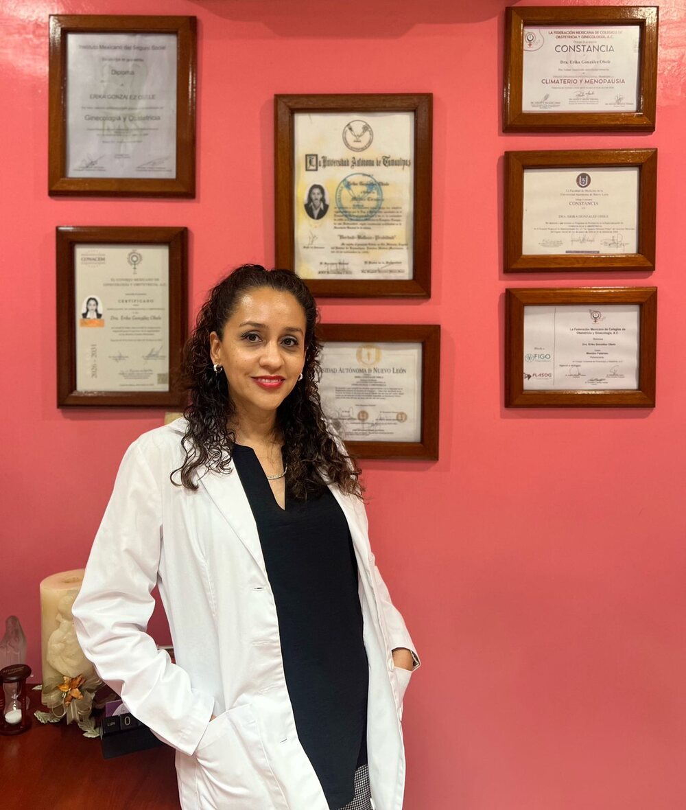 Dra. Erika González Obele frente a sus diplomas y certificaciones médicas